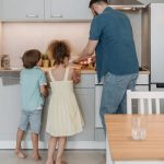 Father and children cooking together in a modern kitchen, enjoying family time.