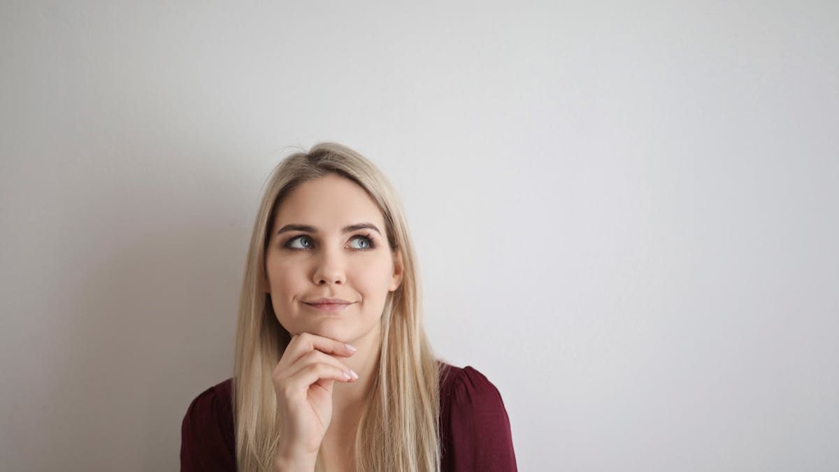 Portrait of a pensive woman with a thoughtful expression against a white background.